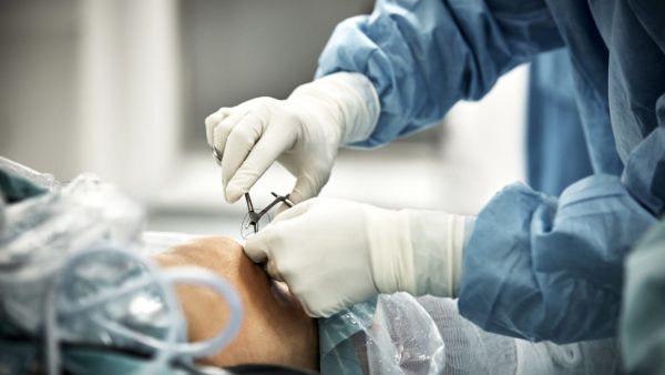 Cropped hands of surgeon stitching patient in operating room at hospital