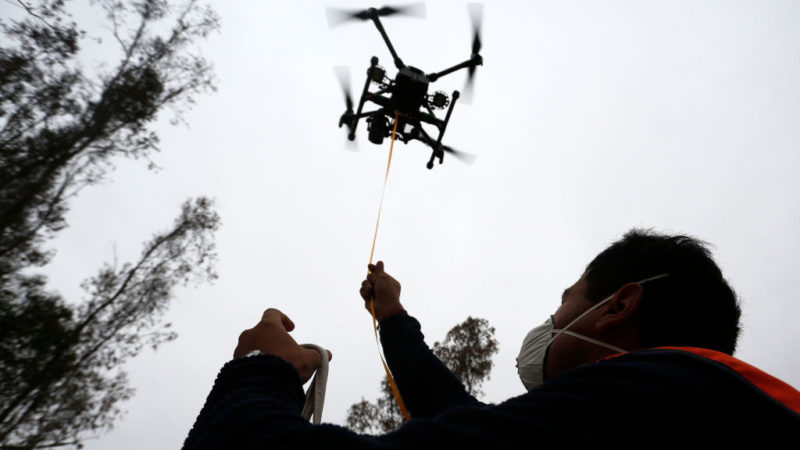 a drone flies in the air over a pilot on the ground