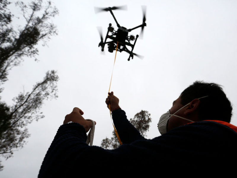 a drone flies in the air over a pilot on the ground