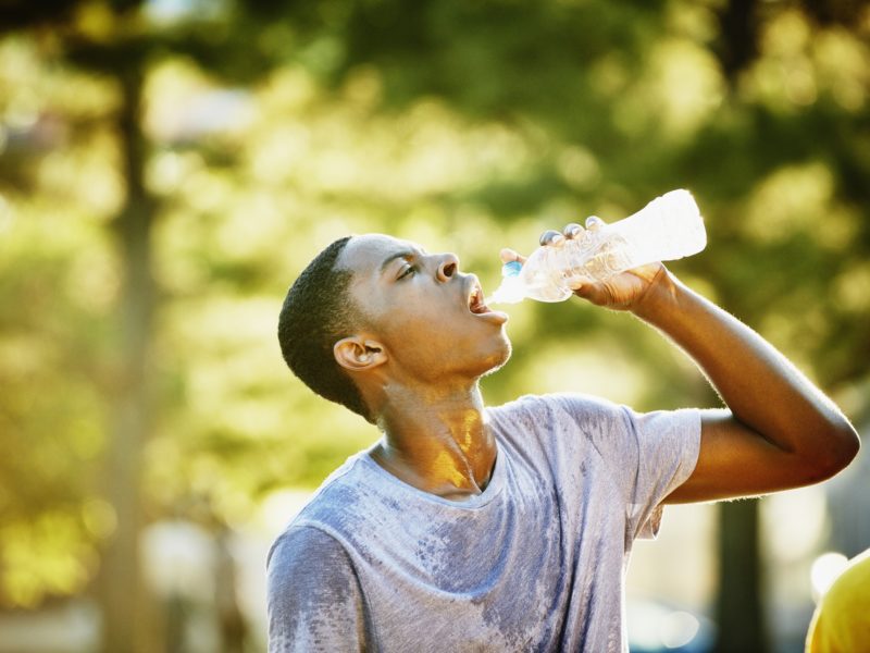 Young man drinking out of a water bottle on a sunny day