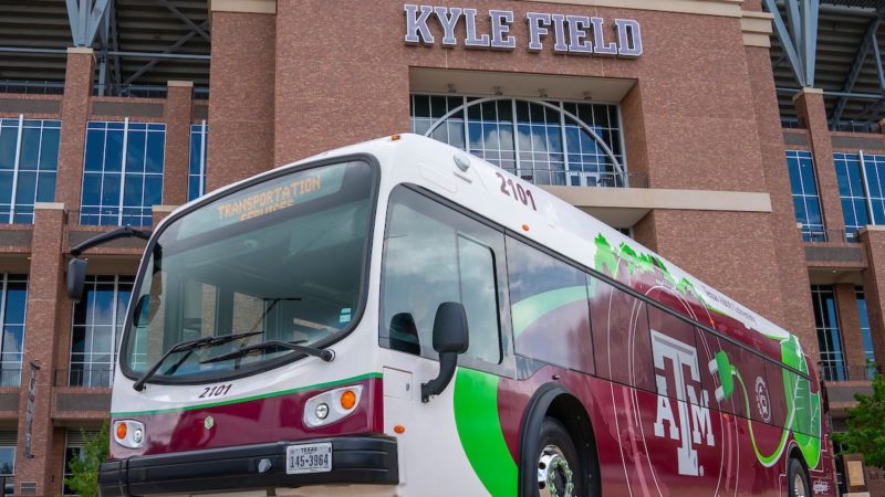 An electirc bus outside of Kyle Field. The stadium is visible in the background