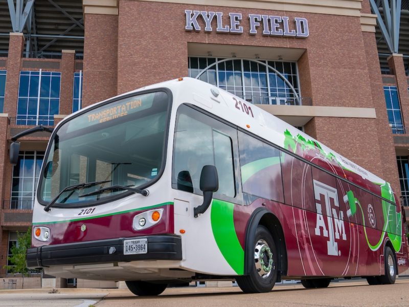An electirc bus outside of Kyle Field. The stadium is visible in the background