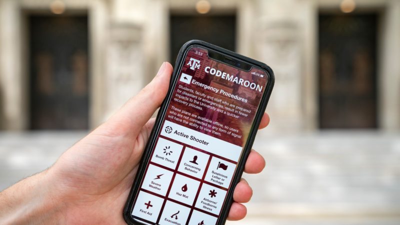 a photo of a hand holding an iphone with the code maroon app open to the emergency procedures screen
