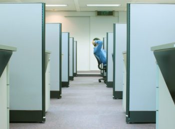 A man reclining in his chair positioned in a row of cubicles in an office