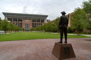 a statue of a soldier overlooks a grassy lawn stretching before kyle field