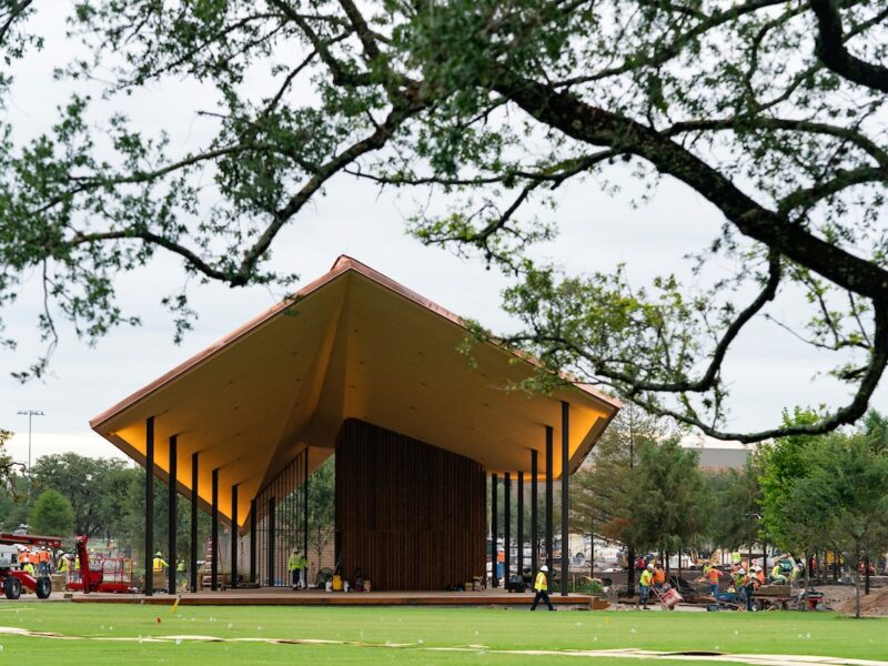 A large amphitheater and stage at the center of the park overlooking a grassy lawn