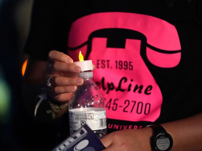 Close-up photo of someone wearing a T-shirt with a graphic of a pink telephone and the HelpLine phone number