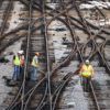 aerial view of railroad workers in yellow vests working on railroad tracks