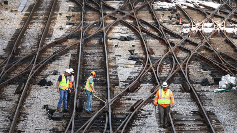 aerial view of railroad workers in yellow vests working on railroad tracks