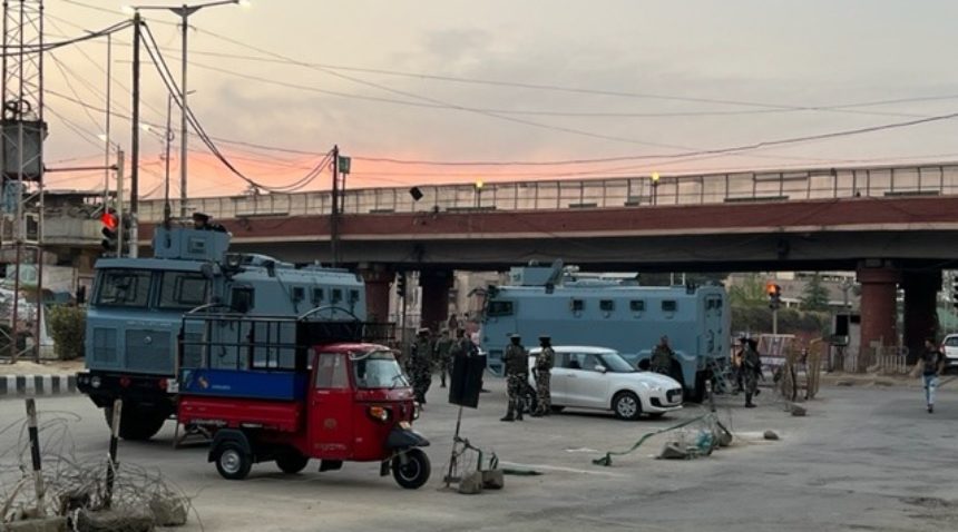a photo showing various vehicles and a group of uniformed guards on a street near an overpass at sunset