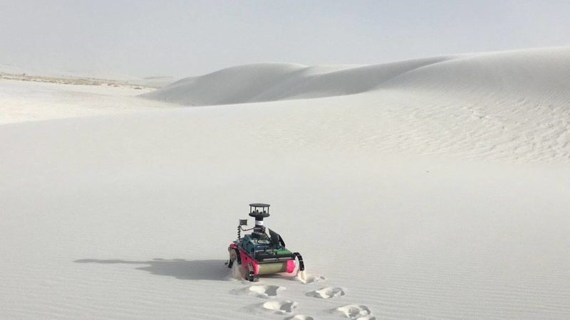 a legged robot on a dune of white sand