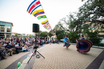 wide angle view of ballet folklorico dancers in colorful dresses performing in front of students in rudder plaza