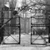 Black and white archival photo of the gates of the concentration camp at Auschwitz
