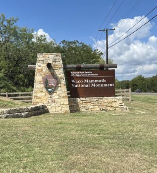 a photo out of a car window showing the Waco Mammoth National Monument sign