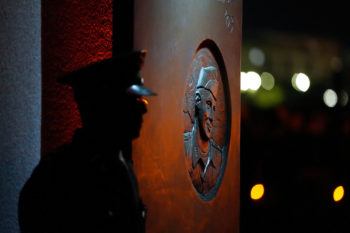 A silhouette of a cadet's profile standing in front of a portal, with the image of a fallen Aggie in the background on the side of a portal.