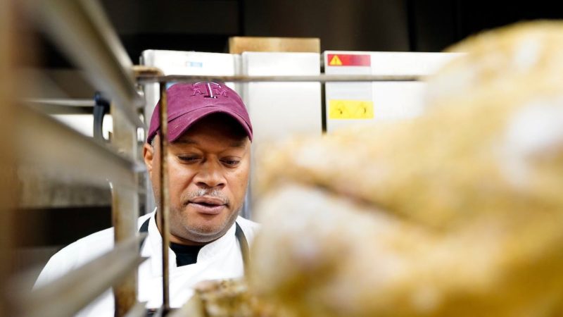 Chef Luke Rayford pictured looking at a turkey on a rack in the foreground