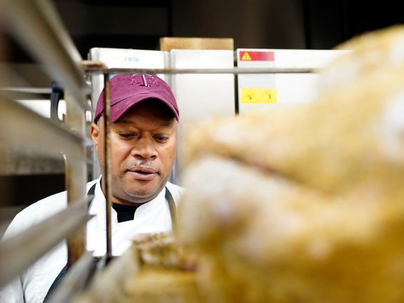 Chef Luke Rayford pictured looking at a turkey on a rack in the foreground