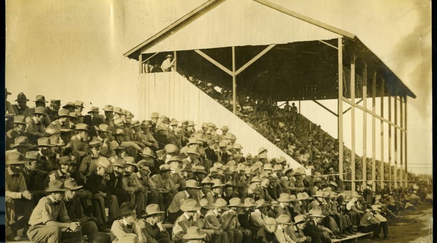 a photo of bleachers and a covered grand stand packed full of people, most of them wearing hats