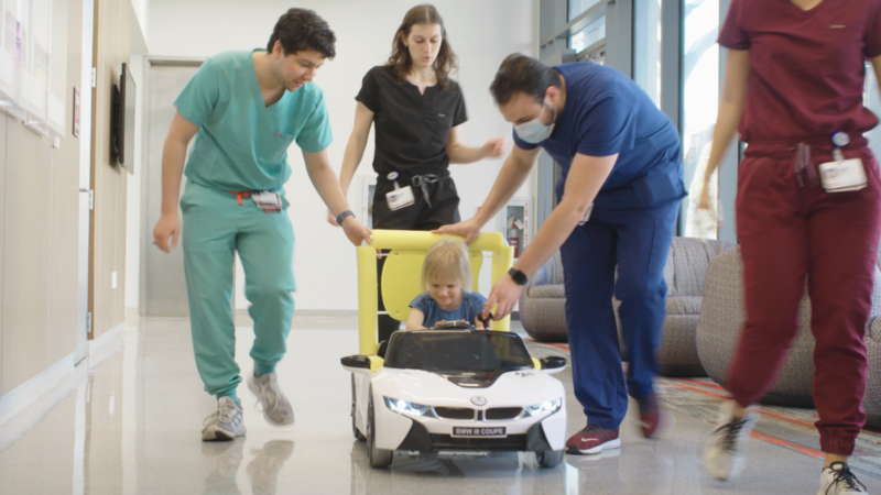 med students with a child in a modified electric car