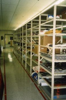 Scanned photo of a storage room with shelving holding boxes of records