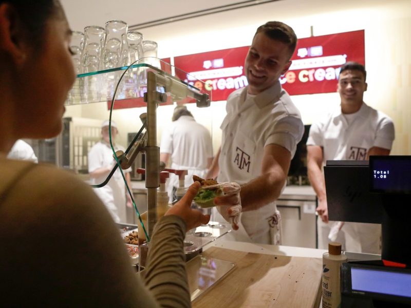A yell leader standing behind a counter hands a student an ice cream cone