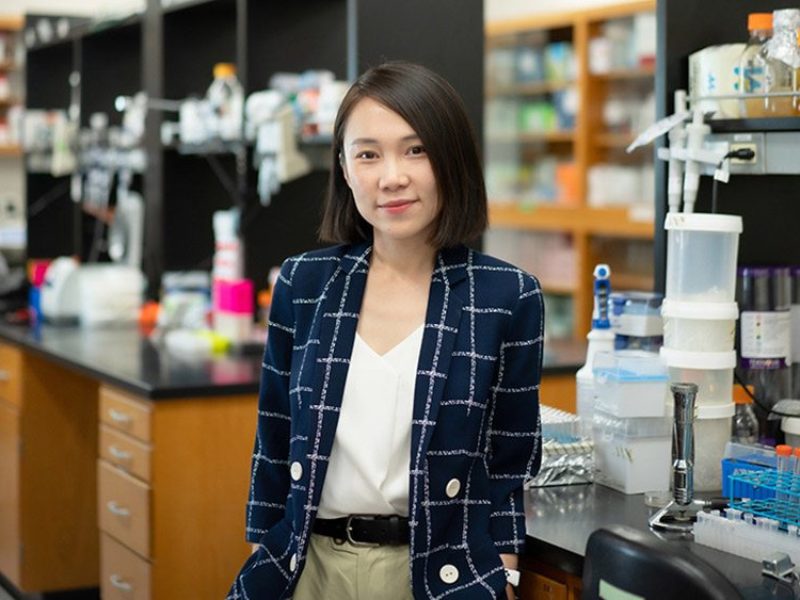Chelsea Hu standing in her lab next to a work bench