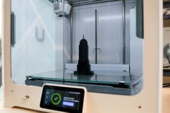 a photo of the interior of a 3D printer with a small black empire state building model inside it