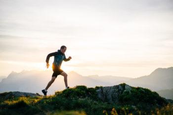 A man runs on a mountain ridge at sunrise