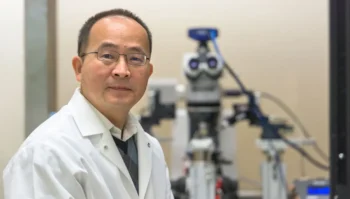 Jun Wang seated in front of a medical device in the background of portrait.