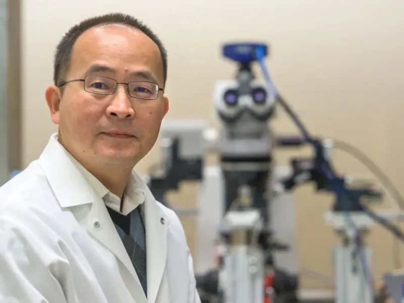 Jun Wang seated in front of a medical device in the background of portrait.