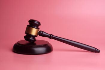 Close-Up Of Gavel Against Pink Background