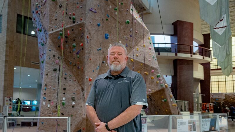 Jeff Huskey in front of the rock climbing wall at the Rec Center