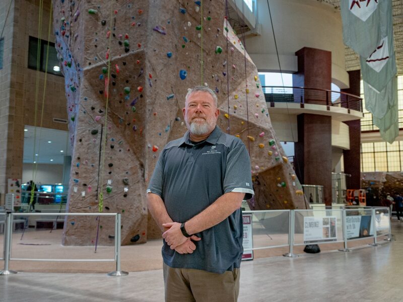 Jeff Huskey in front of the rock climbing wall at the Rec Center