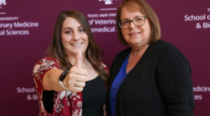 A student giving a Gig 'em thumb with her new ring, posing with a family member