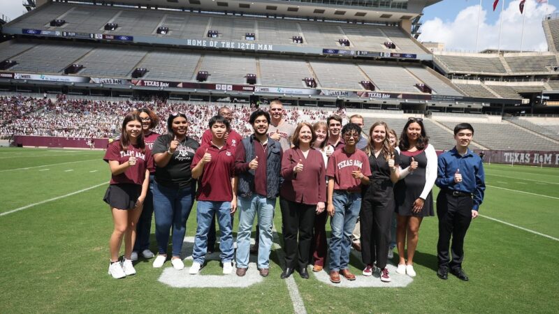 Group photo standing on the 50 yard line of Kyle Field