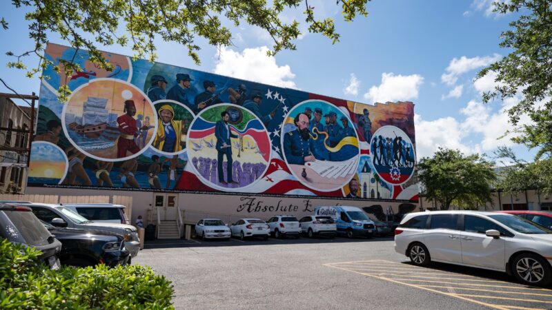 a photo of a colorful mural on the side of a building in Galveston, depicting various scenes related to slavery and emancipation