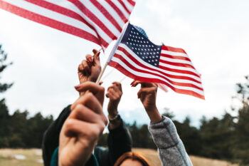 several hands holding small American flags