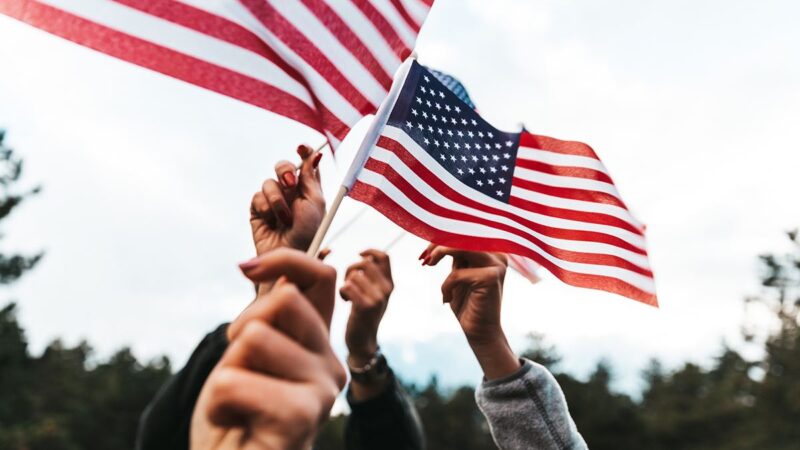 several hands holding small American flags