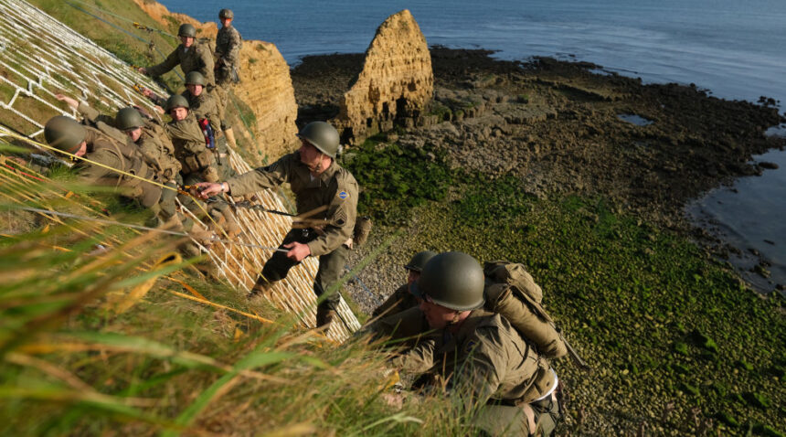 a photo of modern army rangers in WWII uniforms recreating the famous ascent up the cliffs at pointe du hoc