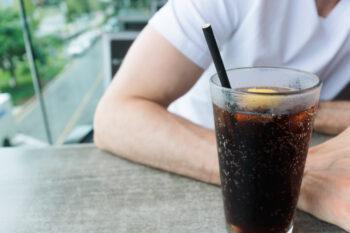 Close-up of unrecognizable white man at restaurant with beverage served with paper straw
