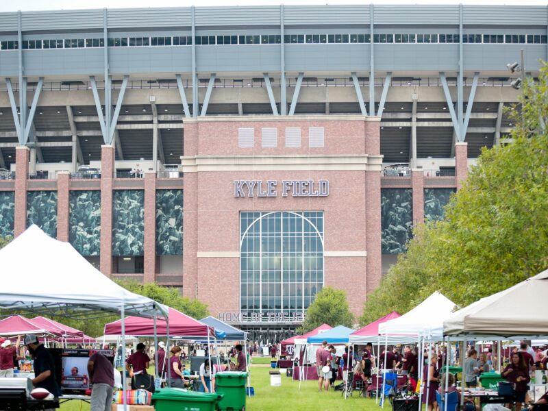 a photo of people tailgating in Aggie Park, with Kyle Field towering over tailgate tents in the background