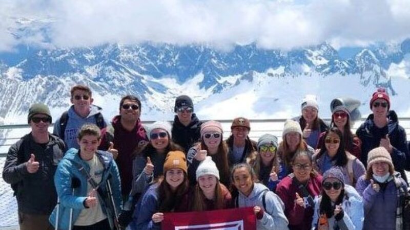 group of Aggies in the alps with an A&M flag