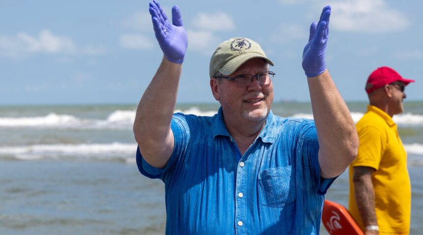 a photo of a man in a blue shirt and gloves clapping