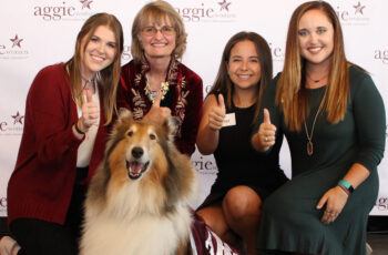 members of Aggie Women Network pose with Reveille at a past luncheon