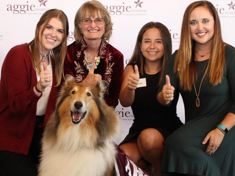 members of Aggie Women Network pose with Reveille at a past luncheon