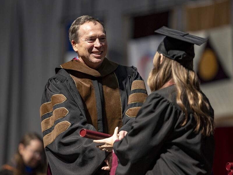 A photo of a Texas A&M student receiving a diploma during a graduation ceremony.