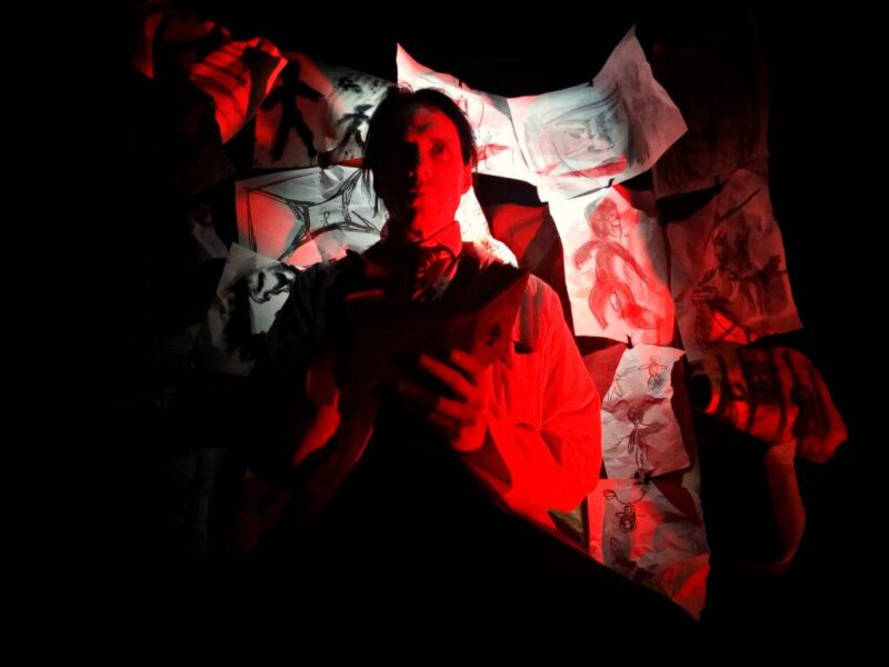 An image of an actor in front of artwork to promote an immersive theater production being performed at Texas A&M University.