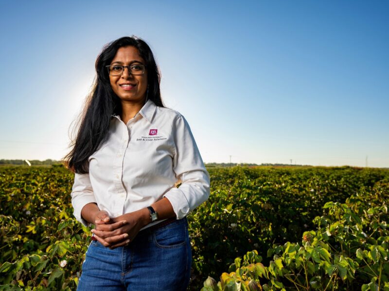 portrait of Nithya Rajan standing outdoors in a field of crops