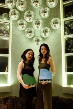 A photo of two women posing with toy pianos.