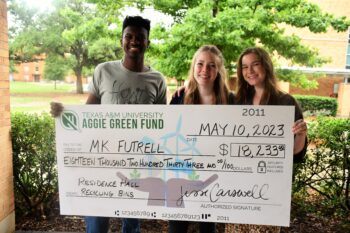Three students holding an oversized check from Aggie Green Fund for$18,233.